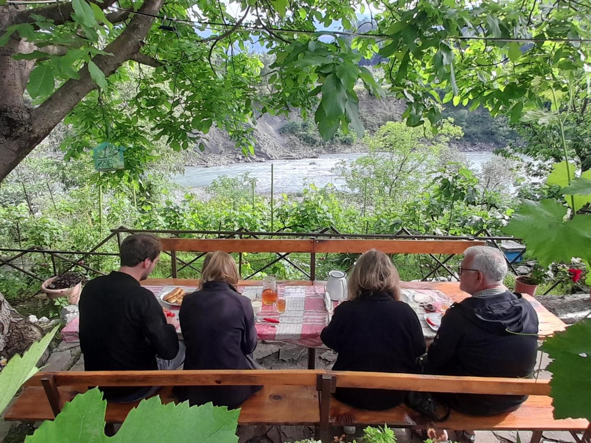 Guests at the garden table above the river